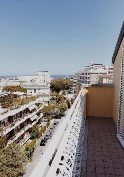 Vista dal balcone su edifici e mare in lontananza.